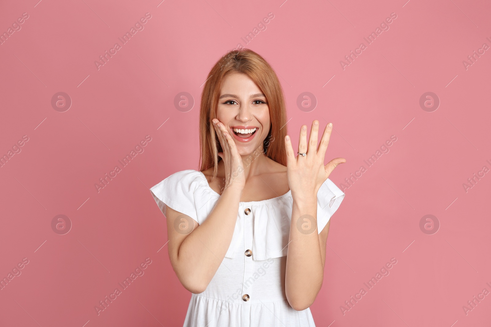 Photo of Emotional woman with engagement ring on pink background