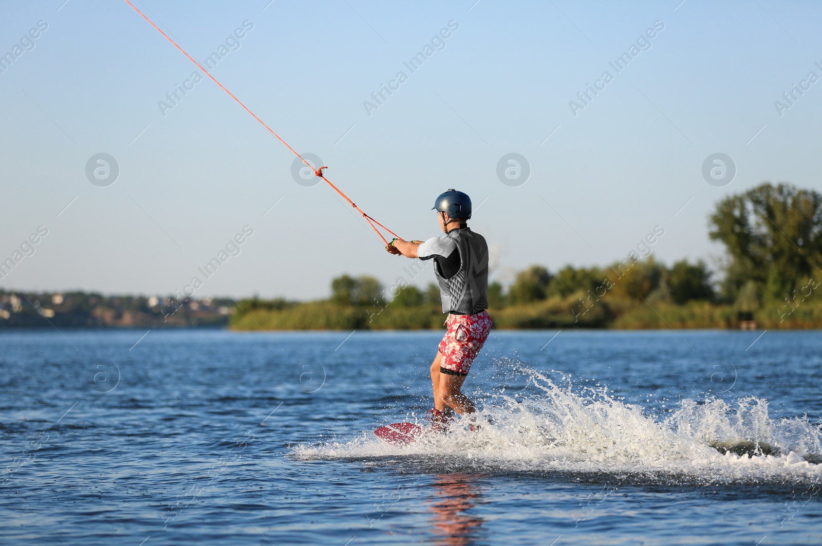 Photo of Teenage boy wakeboarding on river. Extreme water sport