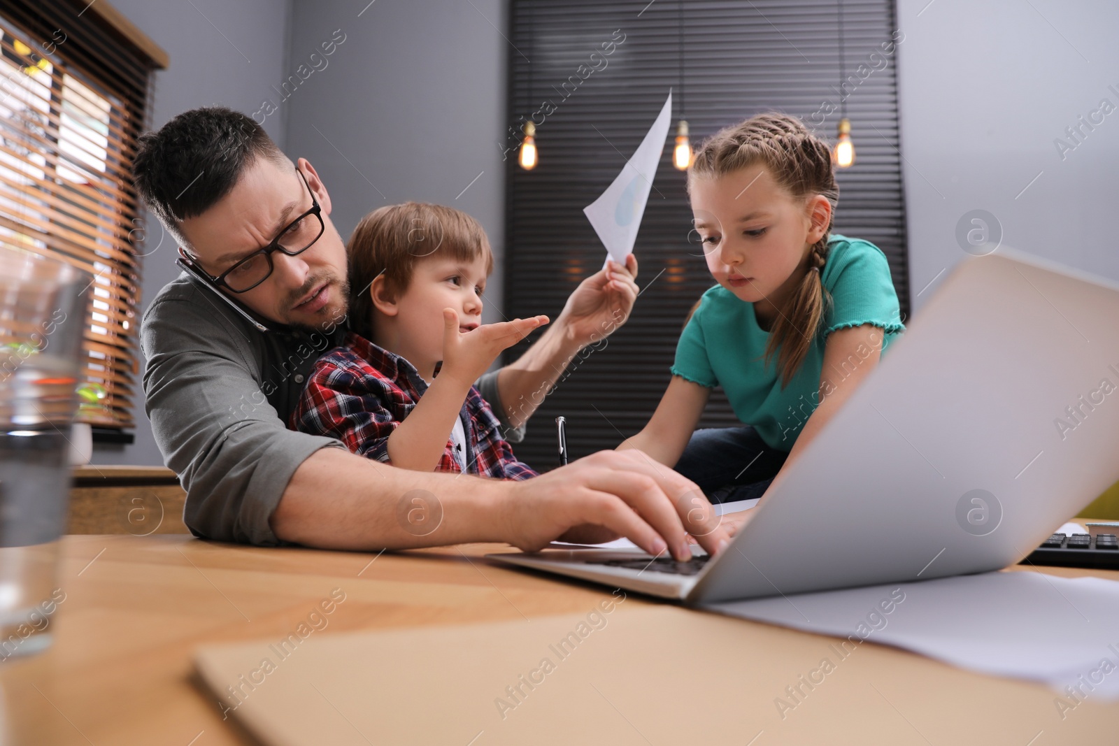 Photo of Overwhelmed man combining parenting and work at home