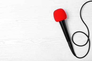 Photo of Modern microphone on wooden background, top view with space for text