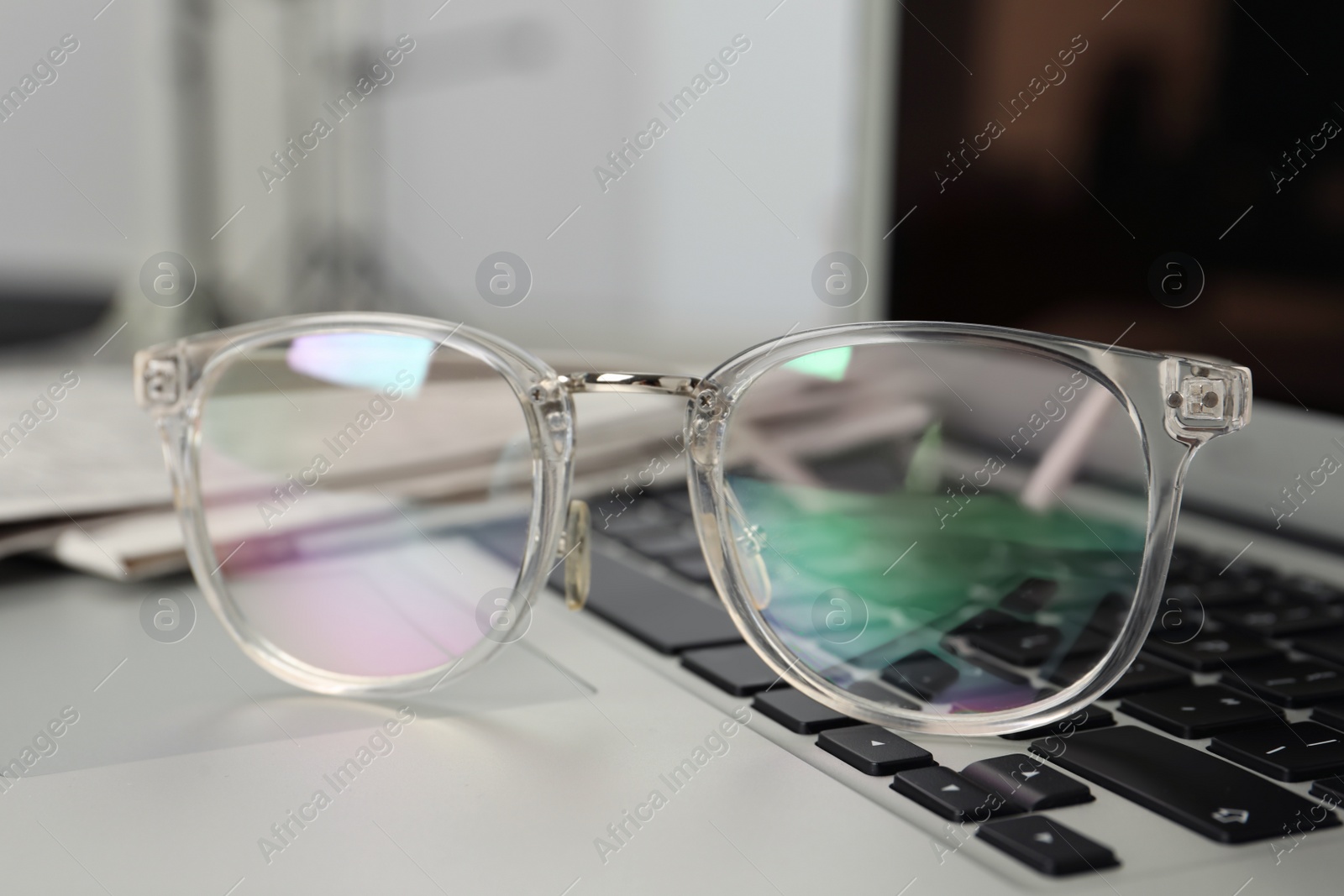 Photo of Glasses and newspapers on modern laptop, closeup