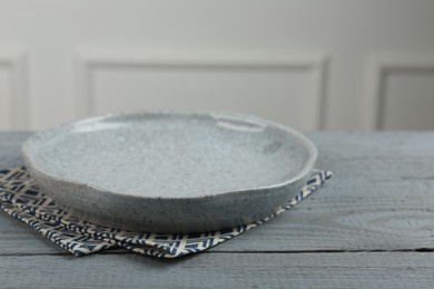 Photo of Beautiful ceramic plate and napkin on gray wooden table indoors, closeup. Space for text