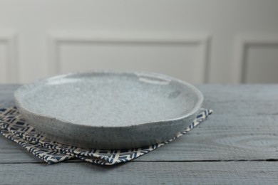 Beautiful ceramic plate and napkin on gray wooden table indoors, closeup. Space for text