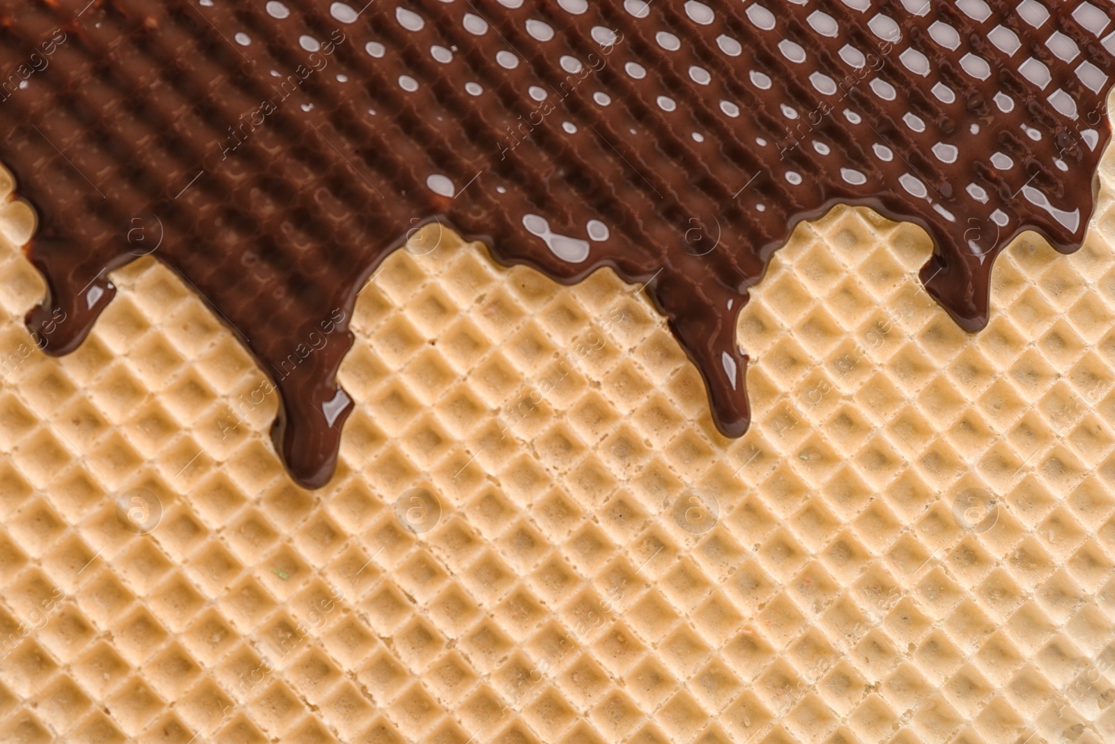 Photo of Hot dark chocolate on wafer, closeup. Crispy food