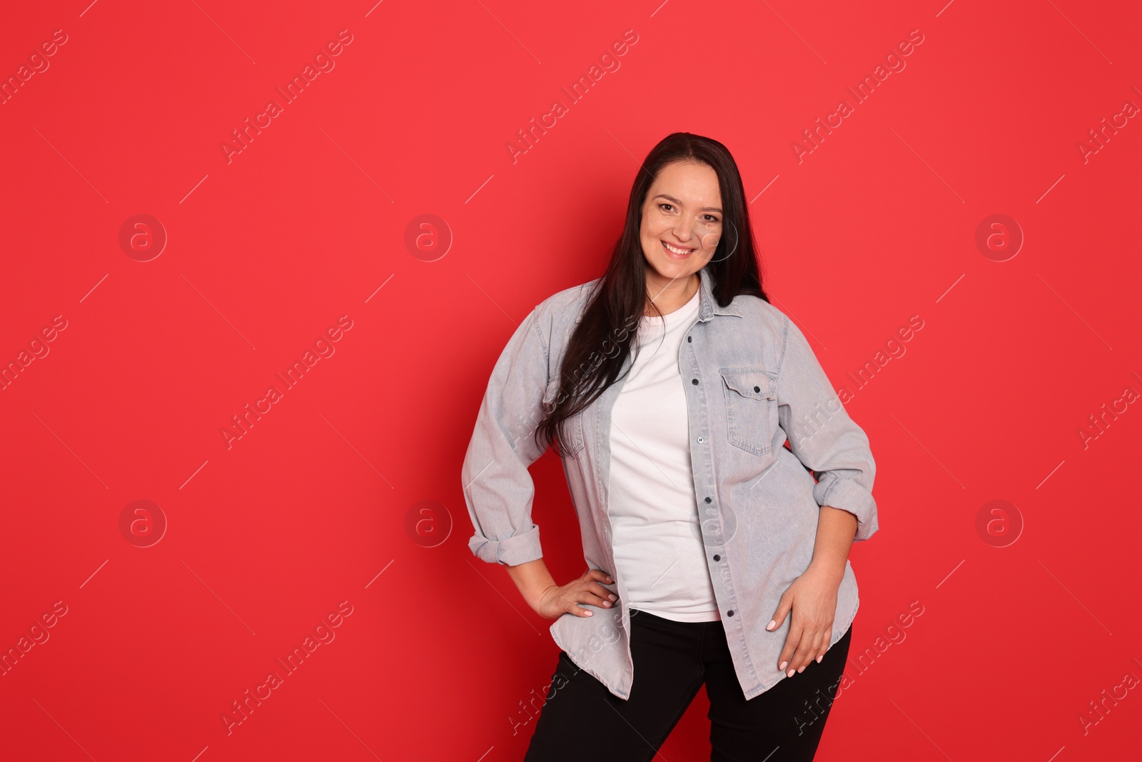 Photo of Beautiful overweight woman with charming smile on red background. Space for text