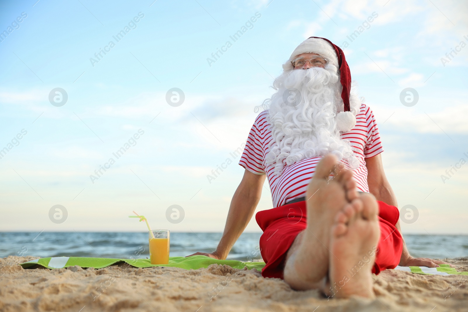 Photo of Santa Claus with cocktail relaxing on beach, space for text. Christmas vacation