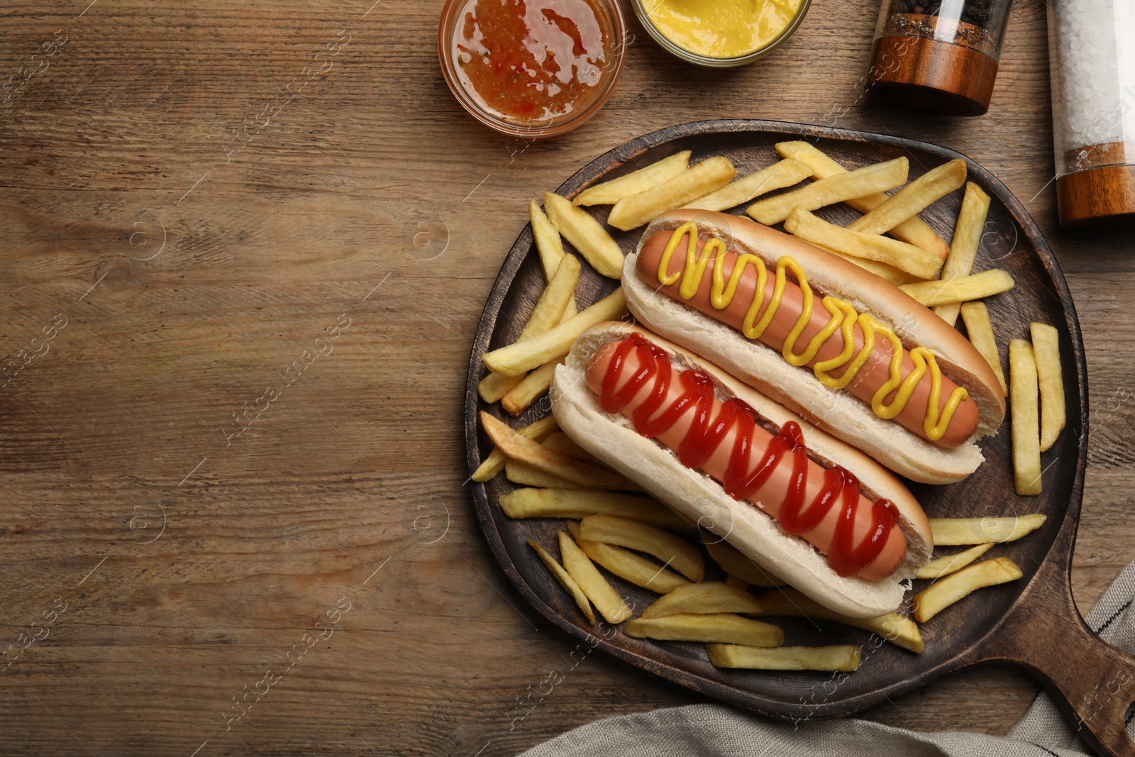 Photo of Delicious hot dogs with mustard, ketchup and potato fries on wooden table, flat lay. Space for text