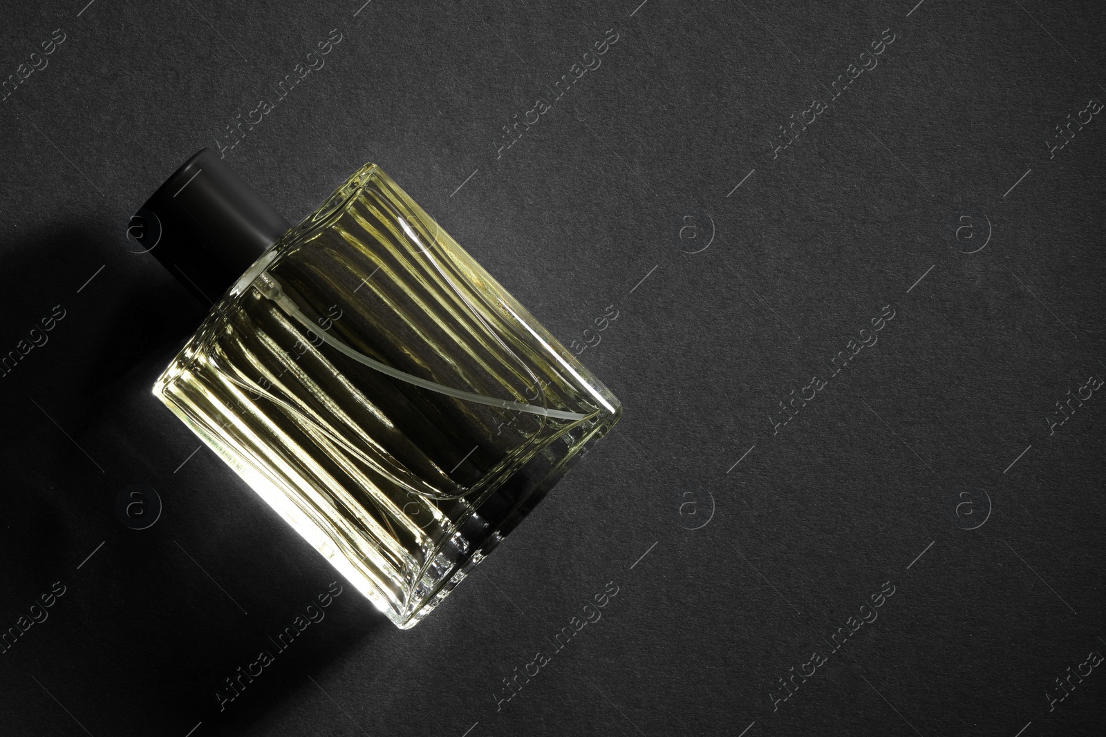 Photo of Luxury men`s perfume in bottle on black background, top view. Space for text