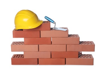 Many red bricks, hard hat and trowel on white background