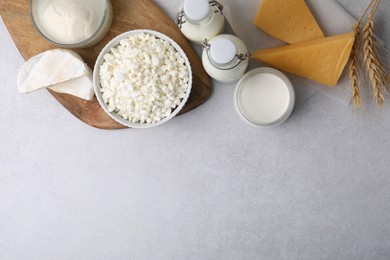 Different fresh dairy products and wheat ears on light table, flat lay. Space for text