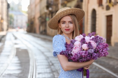 Photo of Beautiful woman with bouquet of spring flowers on city street