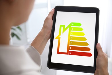 Image of Energy efficiency. Woman using tablet with colorful rating on display indoors, closeup