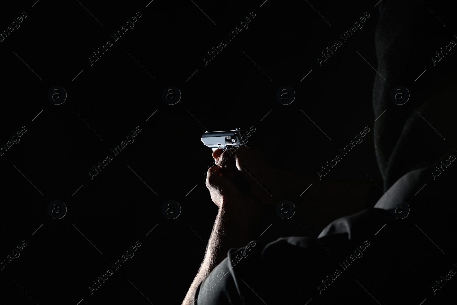 Photo of Professional killer with gun on black background, closeup