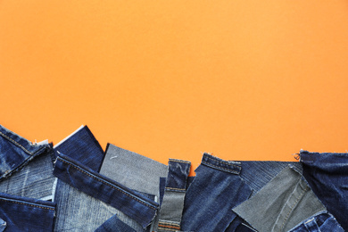 Flat lay composition with patches of old jeans on orange background. Space for text