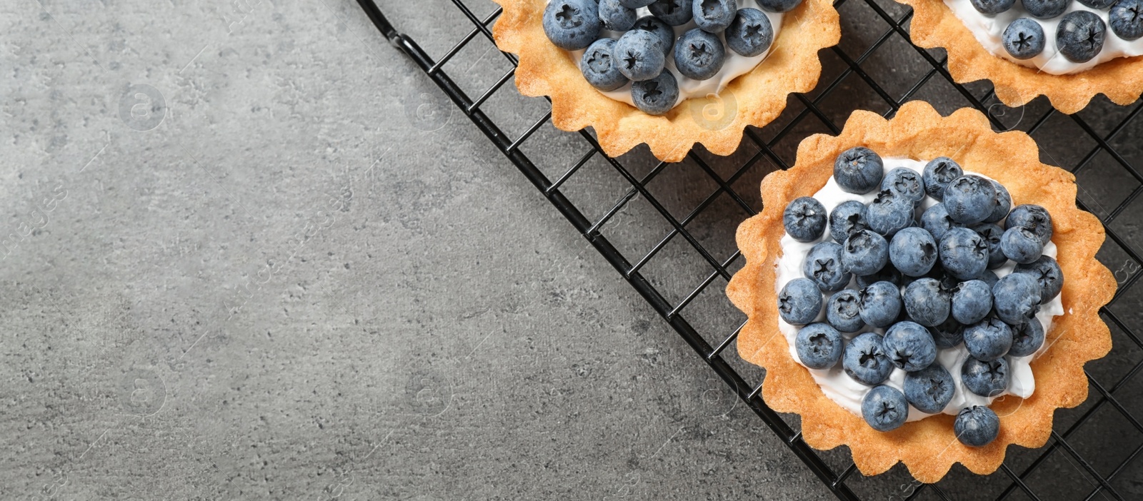 Image of Delicious sweet pastry with blueberries on grey table, top view with space for text. Banner design