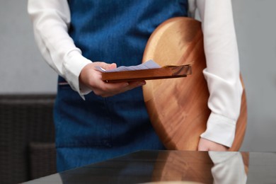 Photo of Waitress holding wooden tray with tips and receipt in cafe, closeup