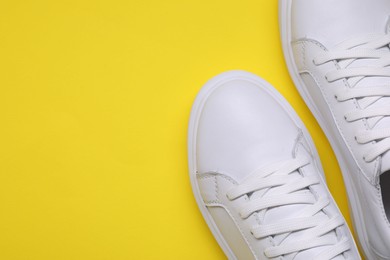 Photo of Pair of stylish white sneakers on yellow background, top view. Space for text