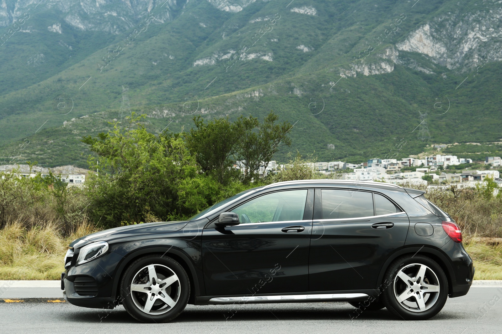 Photo of Beautiful modern black car on road near mountains