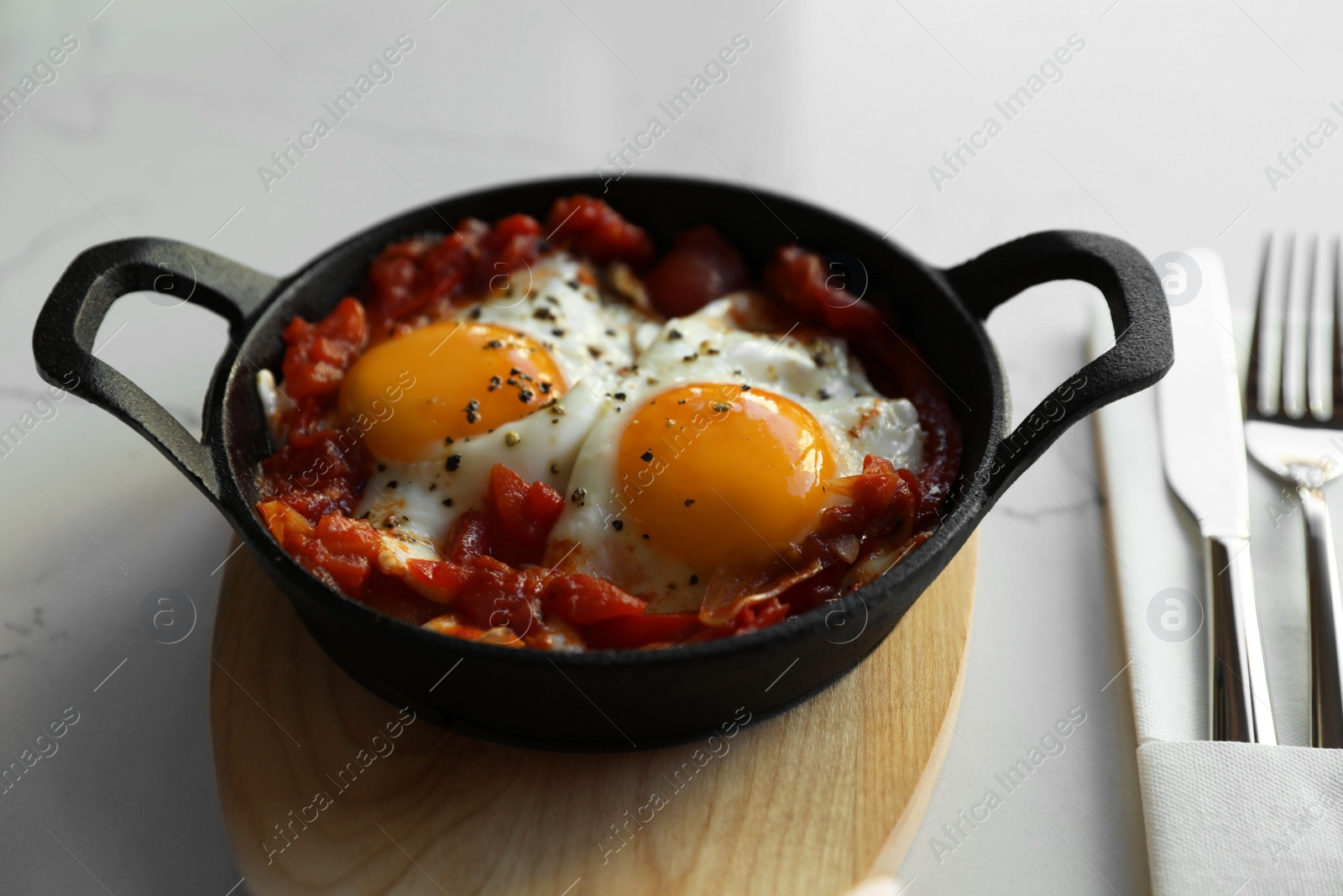 Photo of Tasty Shakshouka served in pan on white table, closeup