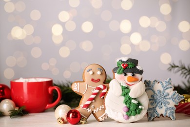 Photo of Sweet Christmas cookies and decor on white table against blurred festive lights