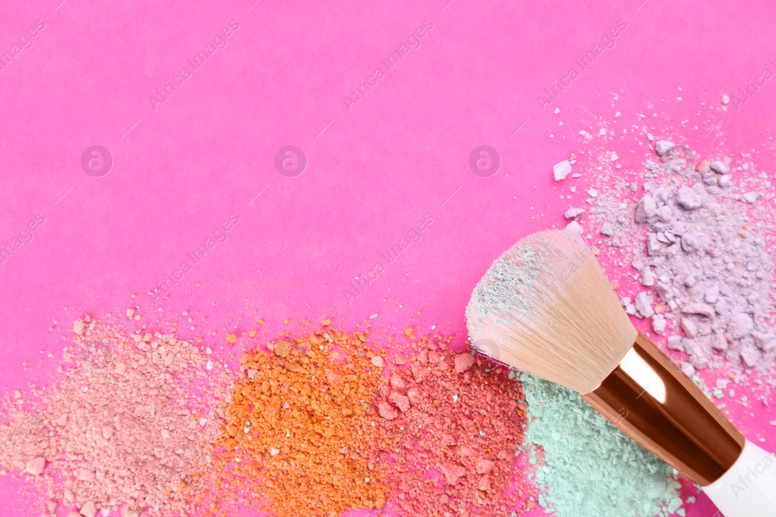 Photo of Makeup brush and scattered eye shadows on bright pink background, flat lay. Space for text