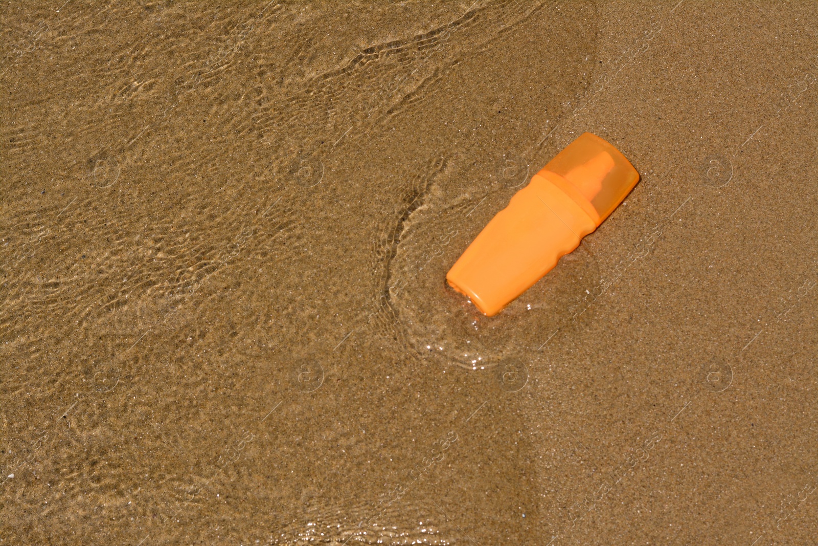 Photo of Bottle with sun protection spray near sea, above view. Space for text