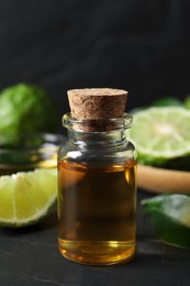 Photo of Bottle of bergamot essential oil on dark table, closeup