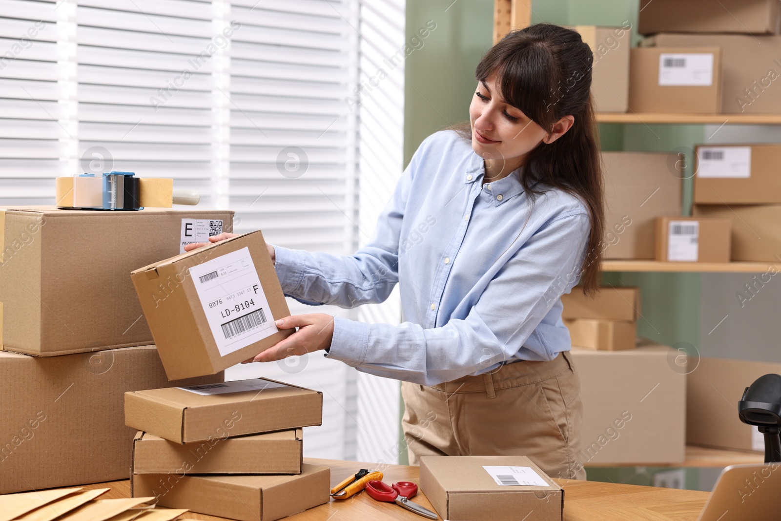 Photo of Parcel packing. Post office with parcels at wooden table indoors