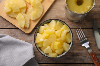 Photo of Flat lay composition with canned pineapple on wooden table