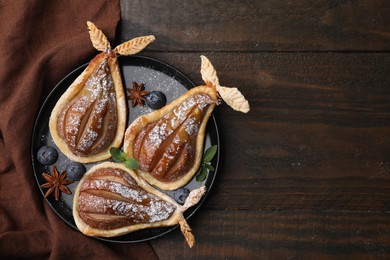 Photo of Delicious pears baked in puff pastry with powdered sugar served on wooden table, top view. Space for text
