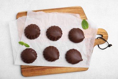Photo of Delicious chocolate covered zephyrs and mint on white table, flat lay