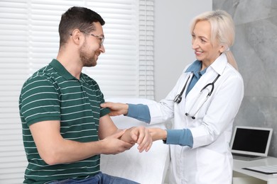 Doctor checking patient's pulse during consultation in clinic