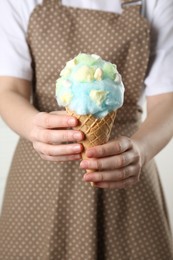 Photo of Woman holding waffle cone with cotton candy, closeup