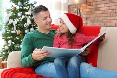 Photo of Father and child reading fairy tales together at home on Christmas day