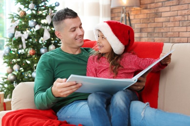 Father and child reading fairy tales together at home on Christmas day