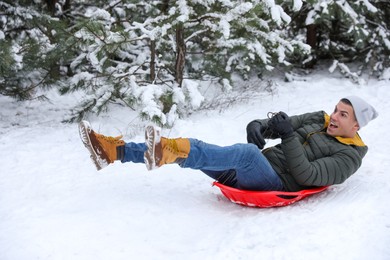 Happy man sledding outdoors on winter day. Christmas vacation