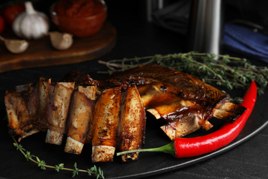 Photo of Delicious roasted ribs served on slate board, closeup