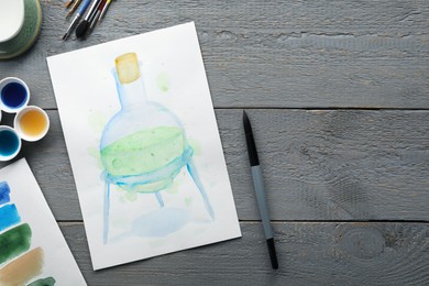 Photo of Flat lay composition with watercolor painting of flask and brushes on grey wooden table. Space for text