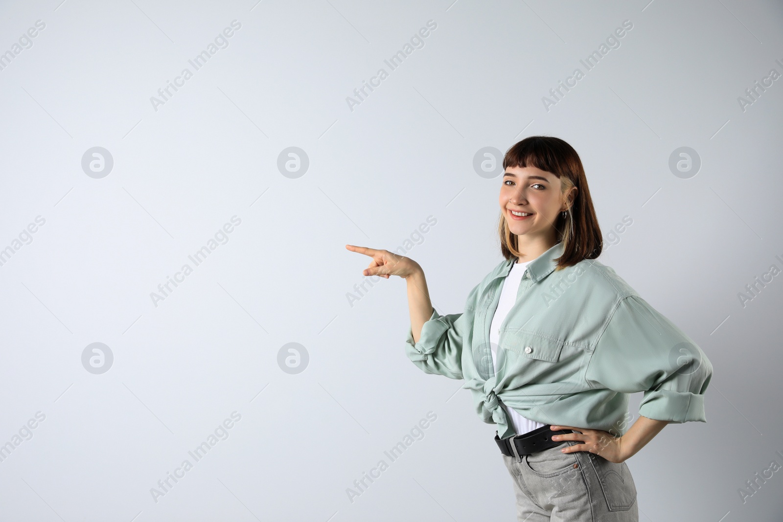 Photo of Beautiful young girl pointing on white background. Space for text