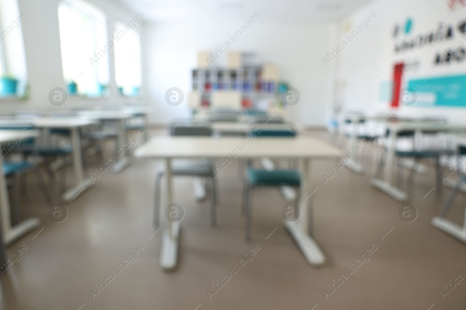 Photo of Blurred view of empty school classroom with desks, windows and chairs