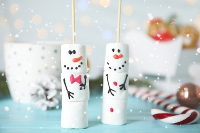 Funny snowmen made of marshmallows on light blue wooden table, closeup