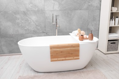 Photo of Different personal care products and accessories on bath tub in bathroom