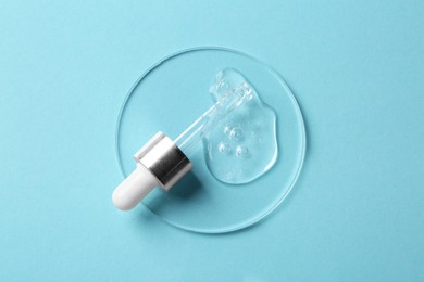 Photo of Pipette with cosmetic serum on light blue background, top view