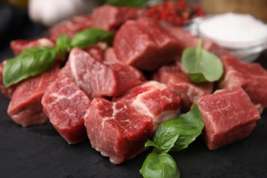 Photo of Cut fresh beef meat and basil leaves on slate plate, closeup