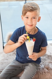 Photo of Little boy with glass of milk shake near window indoors