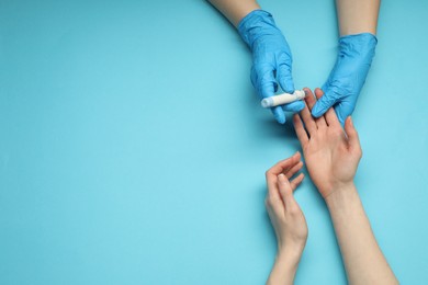 Diabetes. glucose testing. Doctor using lancet pen on light blue background, top view. Space for text