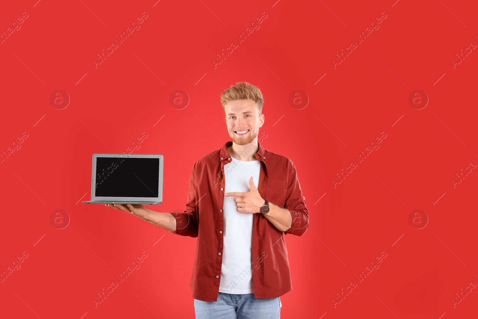 Photo of Happy man with laptop on red background. Space for text