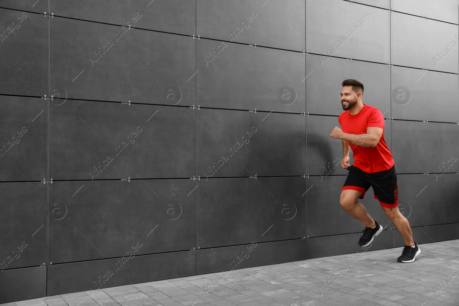 Photo of Happy man running near building outdoors. Space for text