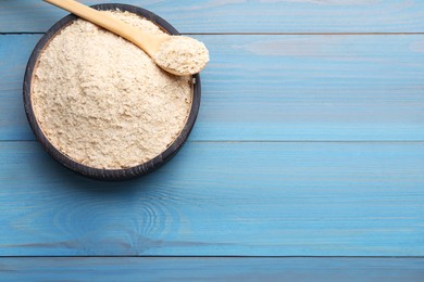 Photo of Bowl of brewer's yeast flakes on light blue wooden table, top view. Space for text