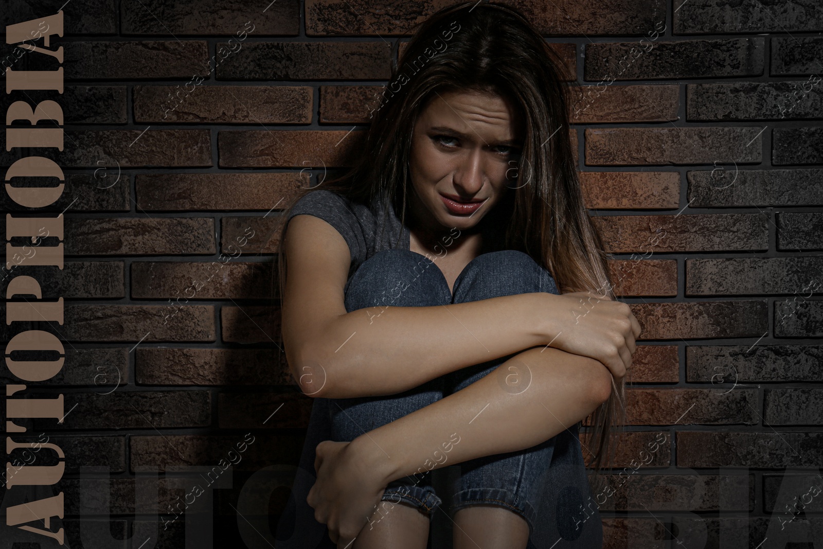 Image of Depressed young woman crying near brick wall. Autophobia - fear of isolation